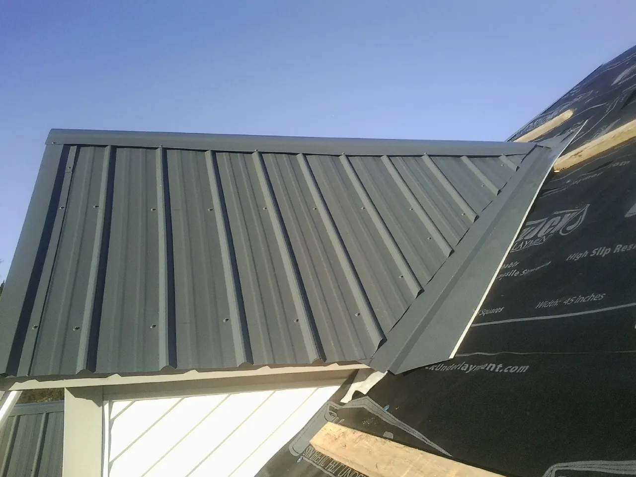 Gray metal roof panels going on over a garage gable in Dowling