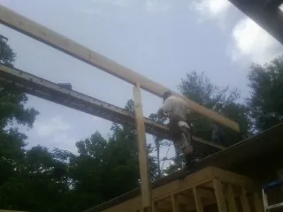 Carpenter setting a ridge beam over a new addition frame — Ice Dam Removal by Roofing Brothers in Dowling