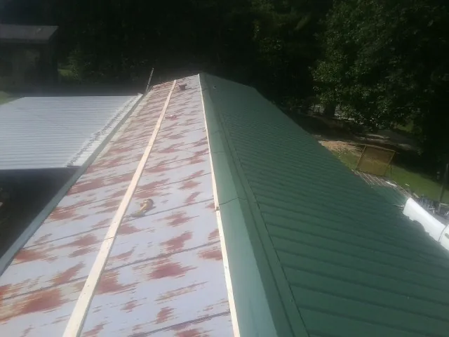 Old rusted panels beside newly installed green metal roofing — Wind Damage Roof Repair by Roofing Brothers in Dowling