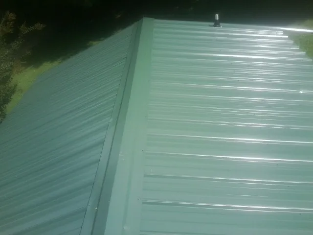 New green metal panels meeting at the ridge of a roof — Flat Roof Repair work by our crew in Dowling
