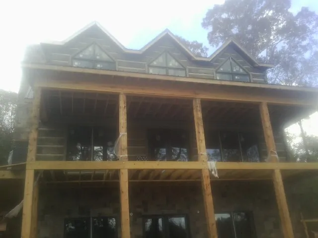 Dormers and porch framing on a large log home under construction — Roof Coating work by our crew in Dowling