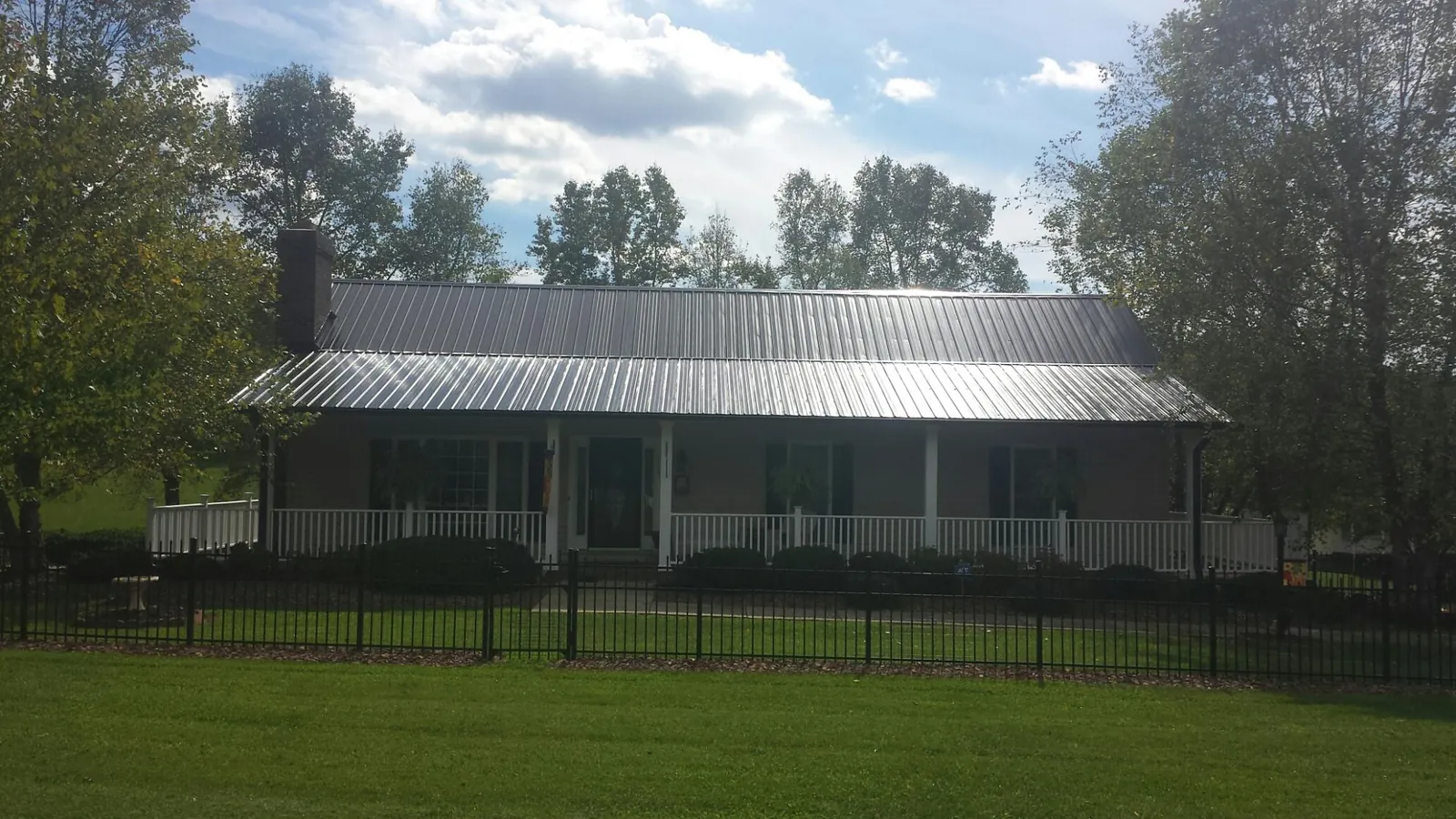 Gray metal roof on a brick ranch with a full width front porch — Gutter Guard Installation work by our crew in Dowling