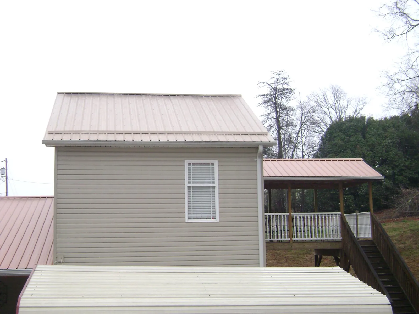 Tan metal roofs on a two story addition and attached porch, from a Roof Replacement job in Dowling