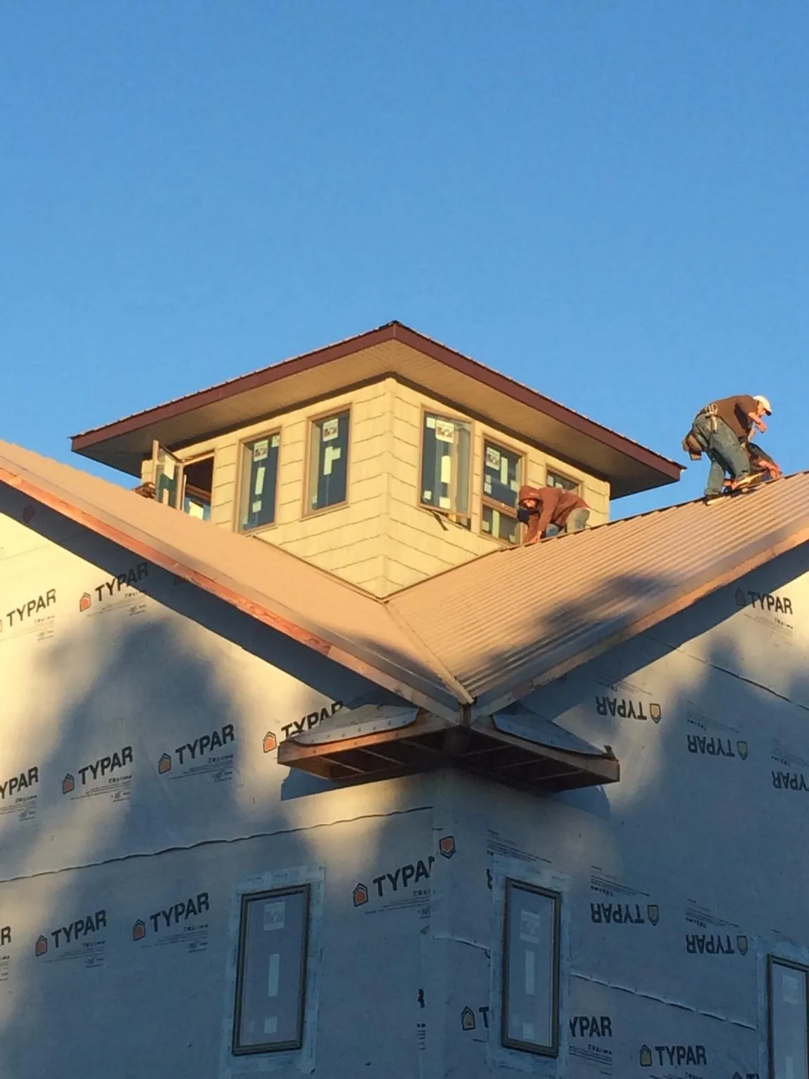 Roofers working around a rooftop cupola on a new metal roof at sunset — Roof Waterproofing in Dowling by Roofing Brothers